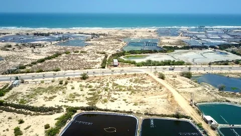 Aerial motion over road between fishing ponds by ocean Stock Footage 104229356