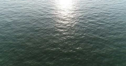 Aerial: motion view over calm, rippled sea, sun reflection Stock-Footage 114427474