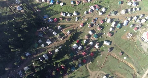 Aerial: motion view over a small village situated among mountains and forests Stock Footage 114374032