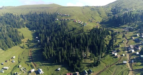 Aerial: motion view over a small village situated among mountains and forests Stock Footage 114498929