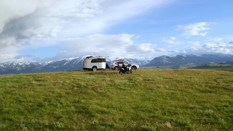 Aerial of motorcyclists and car parking on top of hill with mountains on horizon Stock Footage 124220053