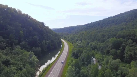 AERIAL: Mountain asphalt road with parallel stormy river and moving car. Stock Footage 78034348