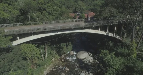 Aerial of mountain bridge over river in forest water flowing beneath concrete Stock Footage 101289034