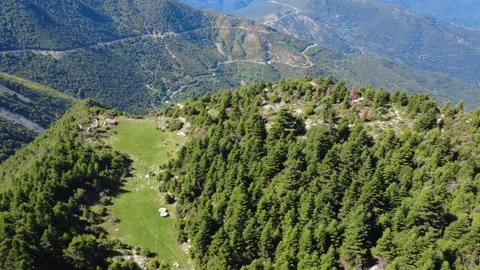 Aerial mountain meadow with remote cabin above dramatic forest gorge Stock Footage 343948266