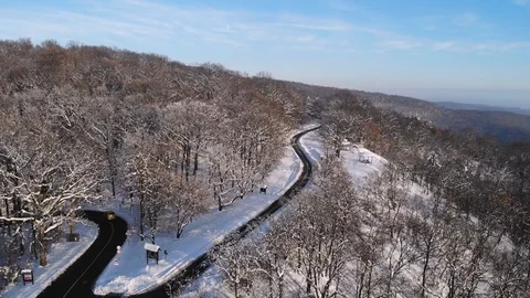 Aerial: mountain pavement road surrounded with snow covered forest. Stock Footage 100240185