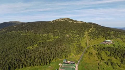 Aerial mountain ridge lodge complex with green roof buildings, forested slopes, Vídeo Stock 345286536