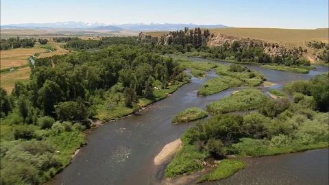Aerial of mountain river flowing through grass field patches, Flight Down Stock Footage 109462701