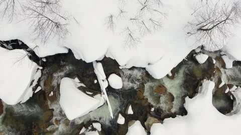 Aerial mountain stream winding through deep snow tunnel - Snowpack and Wildland Stockbeeldmateriaal 339456111