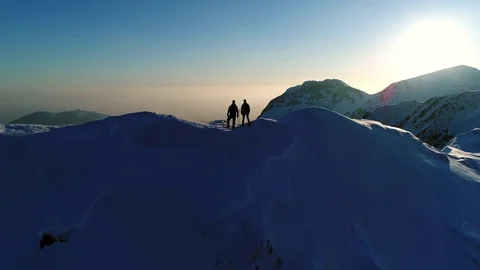 Aerial - Mountaineers high-fiving and celebrating their climb on snowy mountain Stock Footage