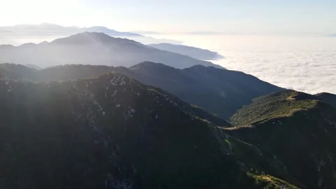 Aerial of mountains above low clouds at dawn Video stock 255849991