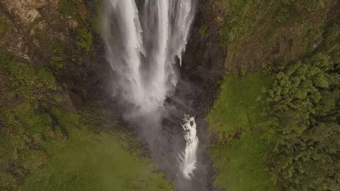 Aerial move along falling water of tropical waterfall Stock Footage
