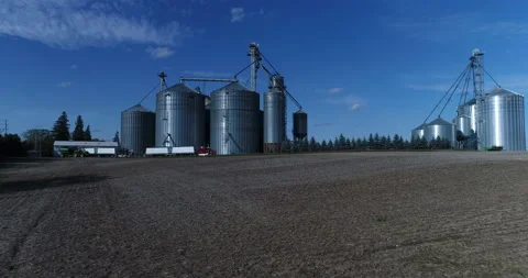 Aerial Move Away From Large Silos Complex Beside Field On A Blue Sunny Day Video stock 199888448