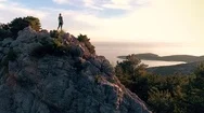 Aerial - Moving Above Woman Standing On Rock Mountain At Seaside Stock Footage