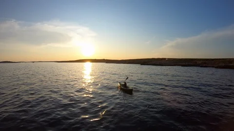 Aerial: Moving away from a person kayaking at sea at sunset Stock Footage 114361153