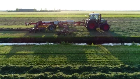 Aerial moving backwards during sundown tractor raking grass to dry it 4k Stock Footage 75910497