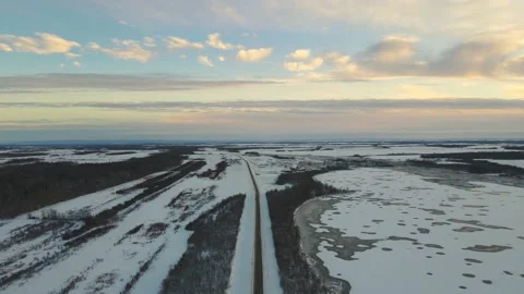 Aerial moving forward above a long paved road surrounded by scrubby looking farm Stock Footage 223437354