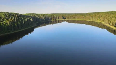 Aerial moving forward above the mirror-like surface of a calm lake Stock Footage 247662199