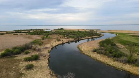 Aerial moving forward above a winding calm river towards a large lake.  Stock Footage 231229305