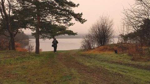 Aerial moving forward behind a man walking towards the lake in the fall. sadness Stock Footage 83654046
