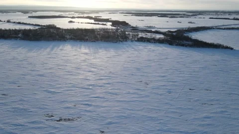 Aerial moving forward high above a frozen lake with a forested shoreline  Stock Footage 228866129