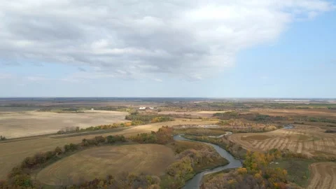 Aerial moving forward high above a river that cuts through harvested farmland.  Stock Footage 251469498
