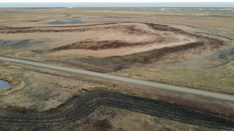 Aerial moving forward over an extensive boggy terrain with a dirt road Stock Footage 230032181