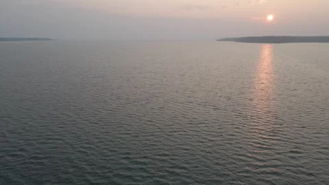 Aerial moving forward over a large lake with waves at sunrise. Misty or smokey. Stock Footage 289028376