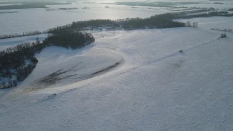 Aerial moving forward over snow covered farmland at dusk with sun low in sky Stock Footage 289028542