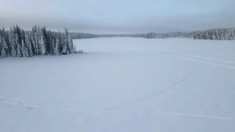 Aerial moving forward then turning left over a frozen snow covered lake  Stock Footage 231229121