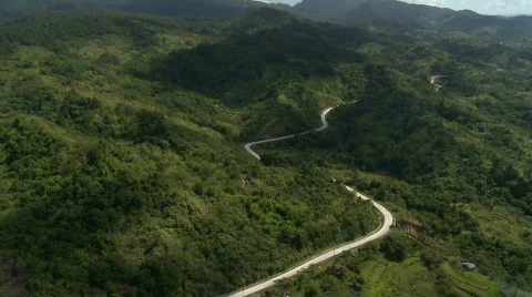 Aerial a nice winding road within a rain forest area with hills Stock Footage 636732