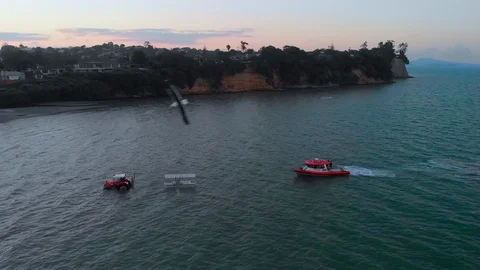 Aerial niew of a tractor pulls a boat out of the sea in Howick's beach in New Ze Stock Footage 100922696