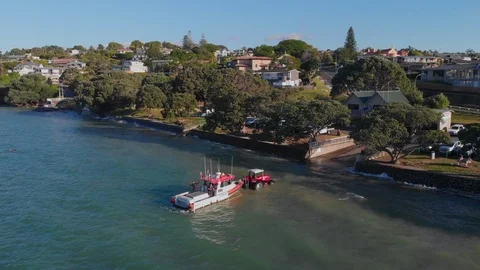 Aerial niew of a tractor pulls a boat out of the sea in Howick's beach in New Ze Video stock 105193780