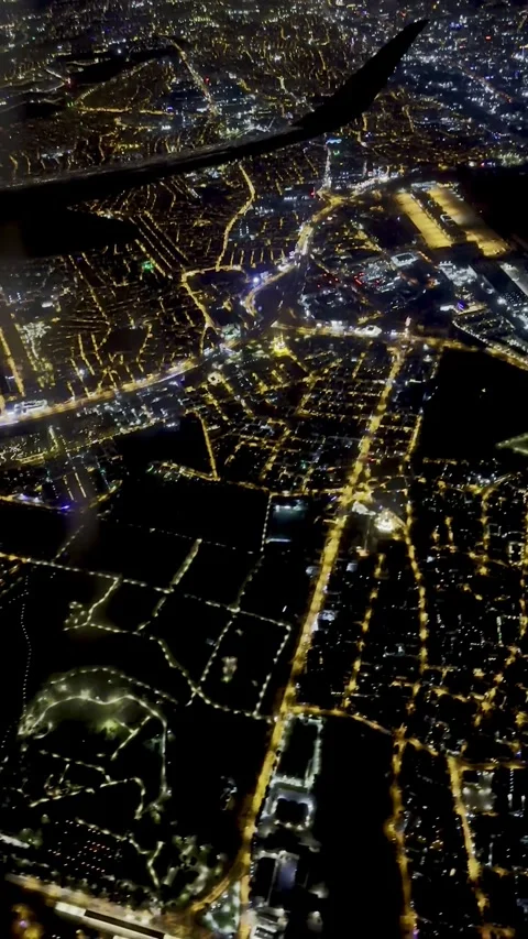 Aerial night view of a sprawling illuminated cityscape from an airplane wing Video stock 345414012