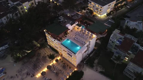 Aerial nighttime view rooftop pool overlooking ocean coastline. City Lights Video stock 271144004