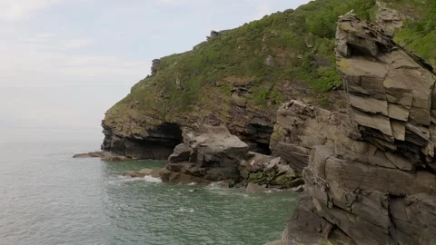 Aerial of the Ocean with Caves in the background , Devon, England 스톡 동영상 251047684