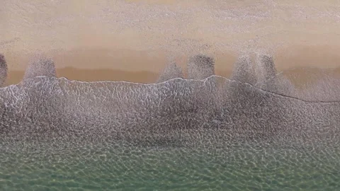 Aerial Ocean Waves Rolling onto Sandy Beach at Golden Hour Stock Footage 325292085