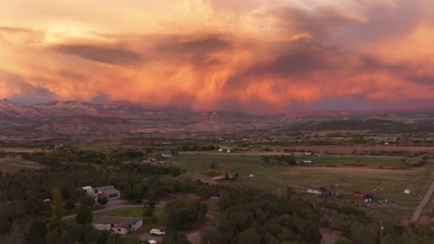 Aerial of orange sunset clouds over rural houses and fields in Mesa Colorado 库存影片 347326782