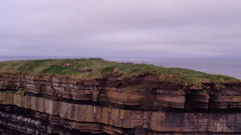 Aerial Orbit and Pullback Over Layered Rocks of Dun Briste Sea Stack Stock Footage 294699820