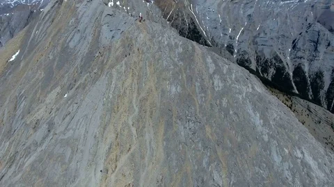 Aerial: Orbit around hikers preparing to follow steep mountain ridgeline Stock Footage 72399072