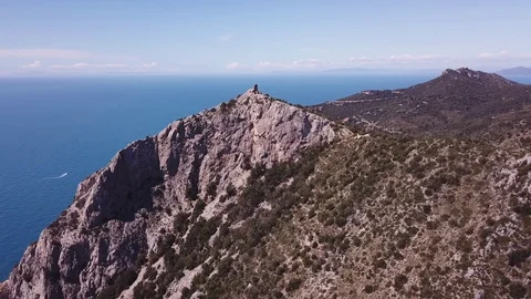 Aerial orbit around a peak with runs of a Tower on a cliff by the sea Stock Footage 107183075