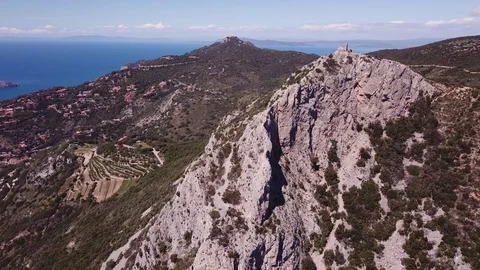 Aerial orbit around a peak with runs of a Tower on a cliff by the sea Stock Footage 107188714