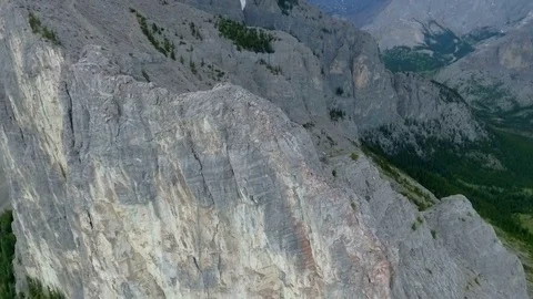 Aerial: Orbit around vertical mountain face with hikers climbing Stock Footage 72402602