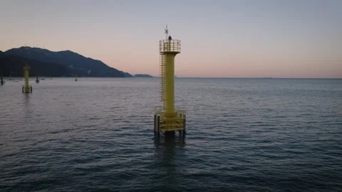 Aerial Orbit Around Yellow Navigation Beacon in Calm Sea at Sunset Stock Footage 340285175