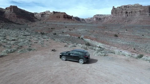 Aerial orbit of black SUV as it drives a remote desert road through great scene Stock Footage 124884513