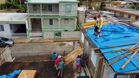 Aerial, orbit, drone shot around volunteers rebuilding a roof of a house, Stock Footage