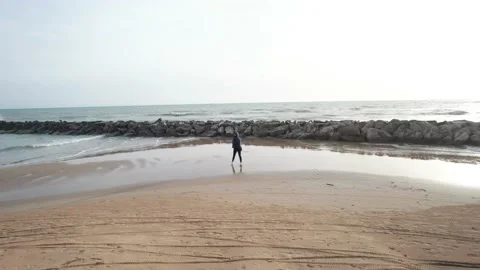 Aerial orbit drone view young girl on sea beach shore sunset rocks Sicily Stock Footage 184449120