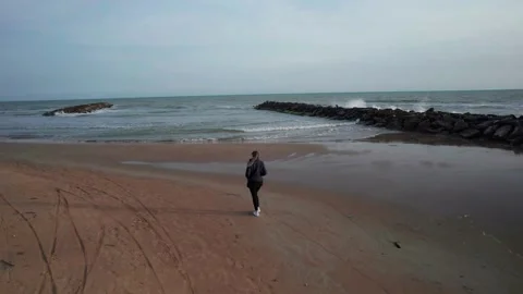Aerial orbit drone view young girl walking on sea beach shore sunset Sicily Stock Footage 184449665