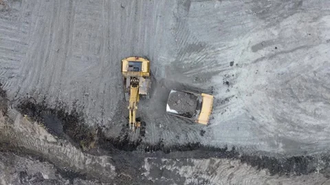 Aerial orbit of excavator loading dump truck in open pit mine Video stock 329550961
