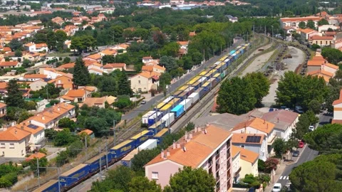 Aerial Orbit of Freight Train Terminal Beside Urban Residential District Stock Footage 336660309