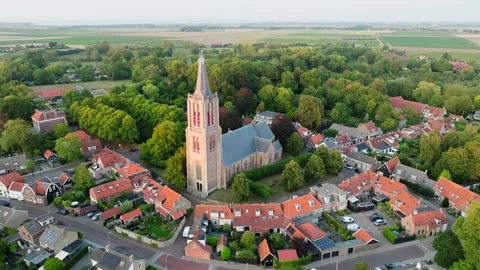 Aerial orbit iconic Dutch protestant church in small city with orange rooftops Stock Footage 316470647